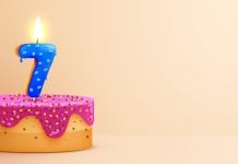 Bolo de aniversário com vela em formato de número 7 acesa