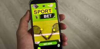 Uma mão segurando um celular mostrando um site de apostas esportivas na tela