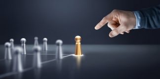 Flutter Brazil fortalece quadro de líderes com duas nomeações Uma mão apontando para bonecos de prata e de ouro sobre uma mesa, representando um líder e sua equipe