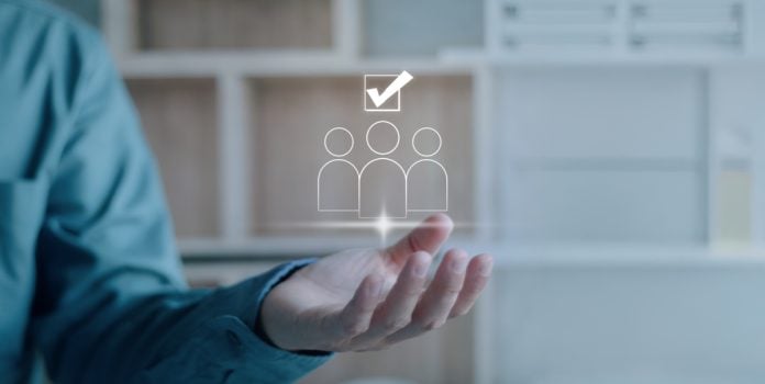 Uma mão projetando três bonecos e o símbolo de aprovado, representando o conceito de excelência em negócios