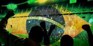 Pinnacle e Rádio 89 FM levam torcedores à Copa do Mundo 2026 Torcedores celebrando com a badeira do Brasil no fundo da imagem