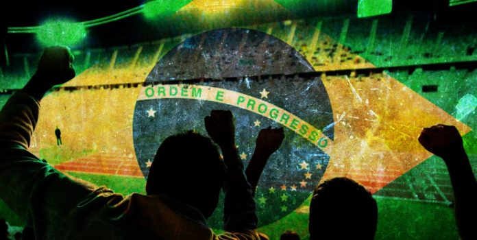 Pinnacle-e-Radio-89-FM-levam-torcedores-a-Copa-do-Mundo-2026- Torcedores celebrando com a badeira do Brasil no fundo da imagem