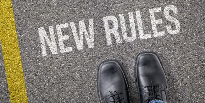 Texto “New Rules” escrito no asfalto e um par de botas pretas