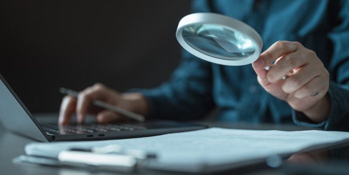 Senacon-Firma-Parceria-com-Conar-Para-Ampliar-Combate-a-Publicidade-de-Apostas-Ilegais Investigador usando lupa.