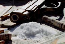 Arma, munições, drogas e dinheiro sobre uma mesa