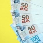 Notas de 50 e 100 reais sobre um fundo amarelo