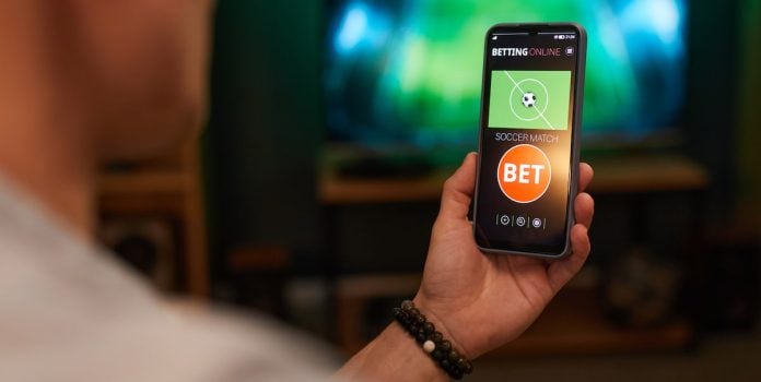 BETBY-Anuncia-Lancamento-do-Watch-Bet-Para-Transformar-Experiencia-das-Apostas-ao-Vivo Pessoa fazendo apostas esportivas em seu celular.