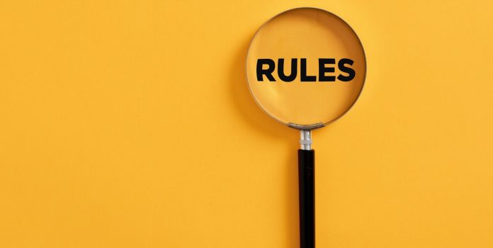 governo-deve-ampliar-regras-para-operadores-apostas Uma lupa em um fundo amarelo, destacando a palavra "regras" em inglês