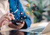 Pessoa mexendo em um celular com ícones de redes sociais sendo projetados do dispositivo