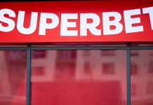 Superbet anuncia linha de acolhimento a apostadores e campanha de R$ 60 milhões para divulgar serviço Letreiro vermelho da Superbet na vitrine, com reflexos.