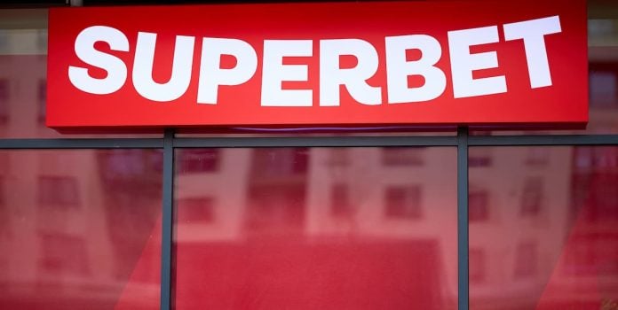 Letreiro vermelho da Superbet na vitrine, com reflexos.