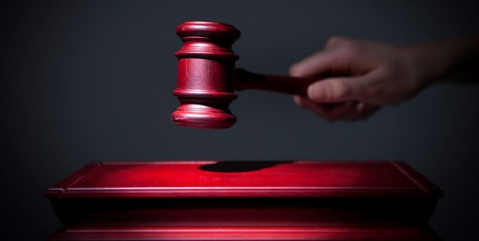 decisão-tjmg-ação-de-apostador-contra-novibet Uma mão segurando um materlo de juiz em um fundo escuro