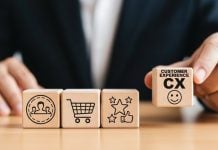 Homem segurando um cubo de madeira com a sigla de Experiência do Cliente em inglês