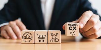 H2bet recebe troféu “Melhores Empresas para o Consumidor” do Reclame Aqui Homem segurando um cubo de madeira com a sigla de Experiência do Cliente em inglês