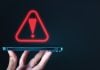 Licença da PixBet é suspensa por falta de documentação e mecanismos de monitoramento Um alerta vermelho sendo projetado em cima de um celular em um fundo escuro