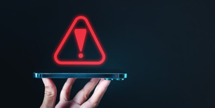 Um alerta vermelho sendo projetado em cima de um celular em um fundo escuro