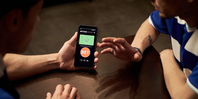 Duas pessoas olhando para o celular pensando em apostar