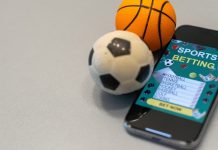 Bola de futebol e de basquete ao lado de um celular com um aplicativo de apostas esportivas.