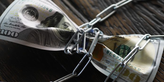 governo-regulamenta-processo-sobre-valores-bloqueados-apostas-ilegais Uma nota de um dólar amarrada em uma corrente