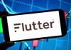Logotipo da empresa Flutter Entertainment exibido em um smartphone.