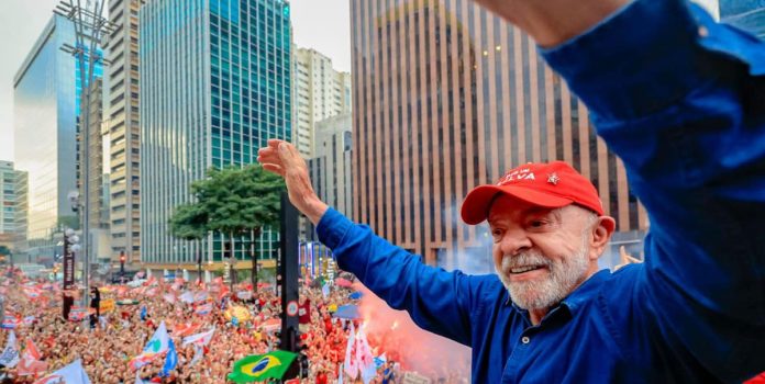 Lula-Derrota-Flavio-Bolsonaro-e-Se-Elege-Para-Quarto-Mandato Lula acena para multidão durante ato de campanha em 2026.