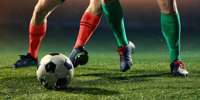 Duas pessoas jogando futebol em um campo