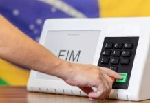 Uma pessoa votando com a bandeira do Brasil ao fundo